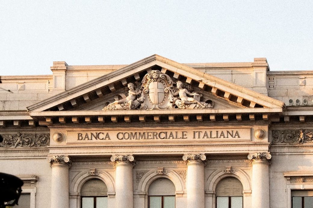 La facciata di un istituto di credito: colonne, finestre ad arco e la bandiera italiana